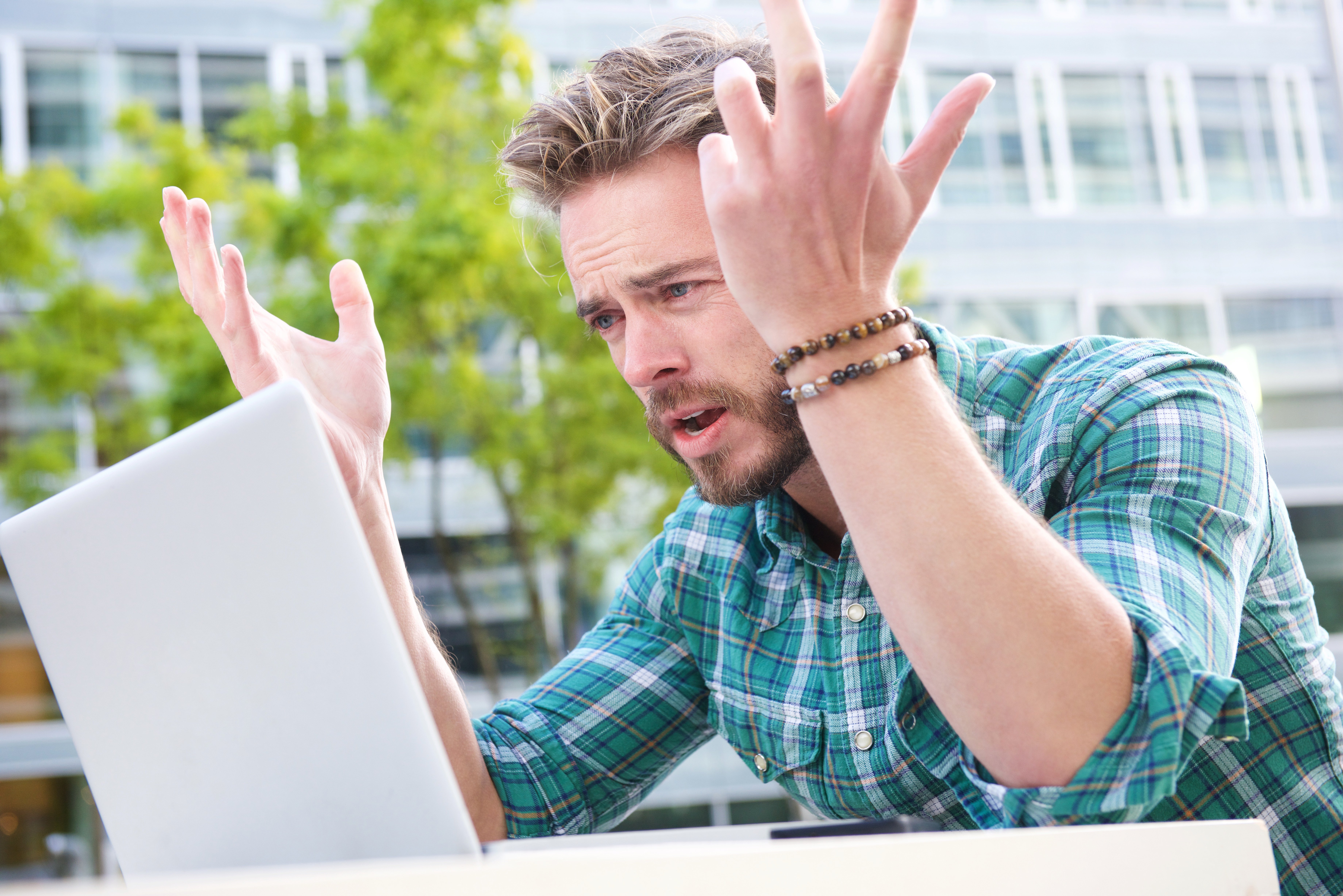 stressed-man-looking-laptop-with-hands-raised